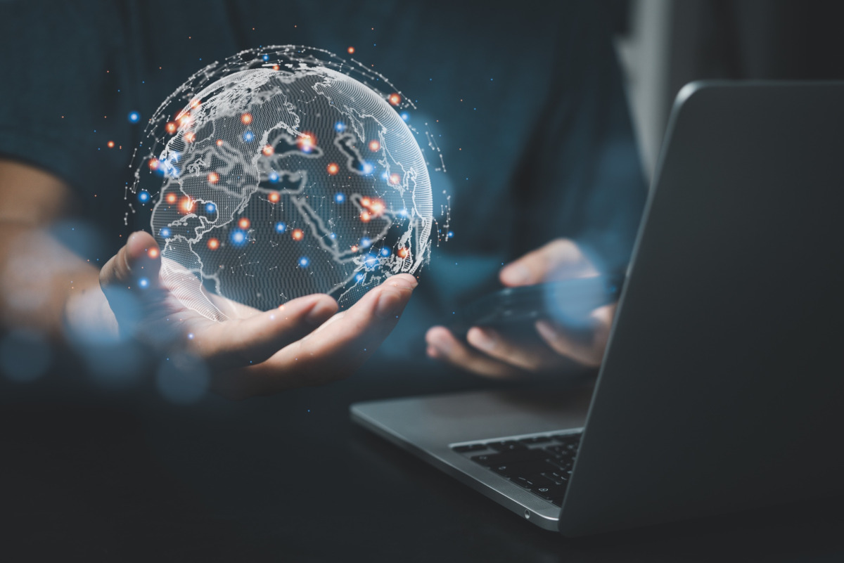 Man working on laptop and holding a digital globe